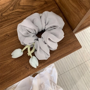 Detail of grey chiffon scrunchie featuring hanging mint green tulip flower charms