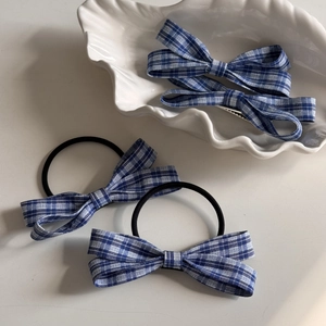 Detail of blue and white checkered bow hair clips and scrunchies set on shell plate