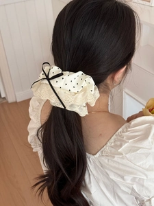 Close-up of cream heart print scrunchie with beige lace trim and black bow on a low ponytail