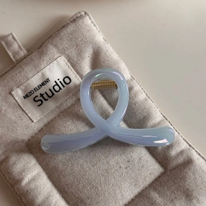 Dettaglio di un fermaglio per capelli azzurro lucido con molla dorata su tessuto trapuntato
