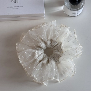 Detailed macro view of white lace scrunchie with polka dot mesh and delicate ruffled edges