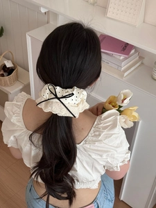 Detail of cream oversized scrunchie with heart print, lace trim and black bow on hair
