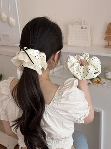 Close-up of cream scrunchie with black hearts, lace trim and elegant black ribbon bow