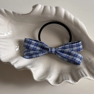 Detail of blue and white checkered bow hair tie with elastic band on shell dish