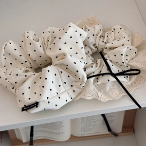 Detail of cream scrunchie set with black heart prints and elegant lace bow hair accessories