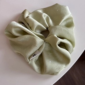 Details von minzgrünem Satin-Haargummi mit Strasssteinen und Logo-Etikett