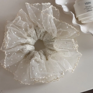 Macro detail of creamy lace scrunchie with white polka dots and scalloped edges