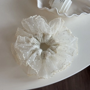 Detail of white lace scrunchie with polka dots and pleated mesh fabric texture