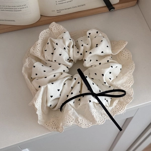 Close-up of cream heart print scrunchie with lace edge and black ribbon bow detail