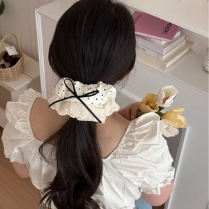 Creamy white oversized scrunchie with black polka dots and lace trim on low ponytail