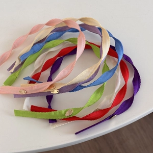 Detailed macro view of colorful grosgrain ribbon headbands with engraved gold metal logo tags