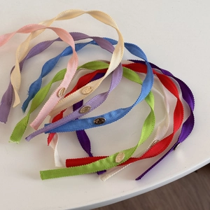 Detail of ribbed fabric headbands with small oval golden metal charms in multiple colors