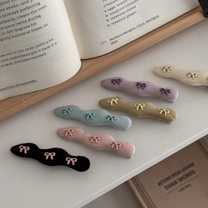 Bunte gewellte Satin-Haarspangen mit Schleifen auf einem weißen Regal mit Büchern