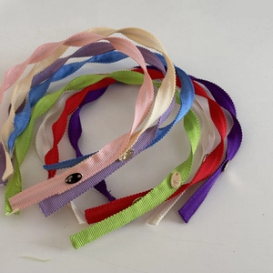 Detailed macro view of spiral fabric headbands with elegant metal branding plates