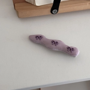 Detailansicht der lila gewellten Stoff-Haarspange mit drei kleinen Schleifen