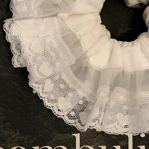 Dettaglio dell'elastico scrunchie in pizzo bianco con eleganti ricami a cuore