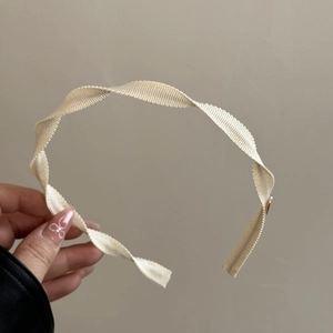 Close-up of beige spiral fabric headband featuring elegant woven texture and twisted design