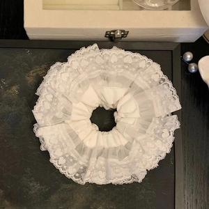 Vista dettagliata dell'elastico per capelli in pizzo bianco a cuore con ruches e perle