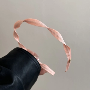 Close-up of pink spiral fabric headband showing fine texture and gold metal buckle