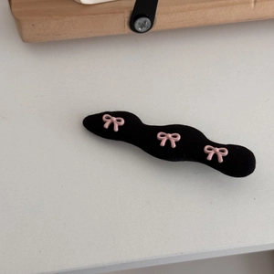 Detailansicht der gewellten schwarzen Haarspange aus Stoff mit drei rosa Schleifen