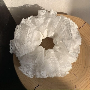 Elegante elastico in pizzo bianco con ricami floreali su un supporto tondo in legno