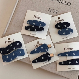 Detail of denim hair clips with white heart patterns in various shapes on a card