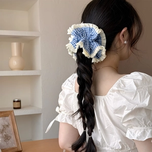Chouchou à carreaux bleus avec bordure en dentelle sur une coiffure tressée