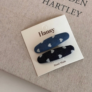 Detail of two denim heart hair clips on display card with white printed patterns
