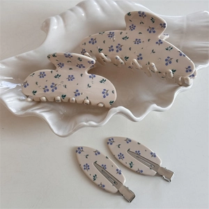 Détails des pinces à cheveux avec fleurs bleues et strass sur une assiette coquille