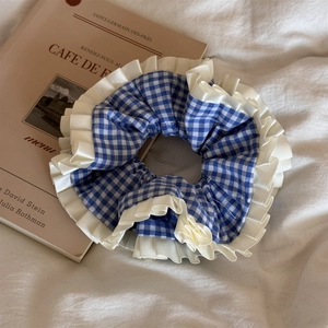 Détail d'un chouchou à carreaux bleu et blanc avec des bordures en dentelle blanche