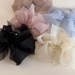 Makroaufnahme großer Chiffon-Haarspangen in fünf eleganten Farben auf elfenbeinfarben