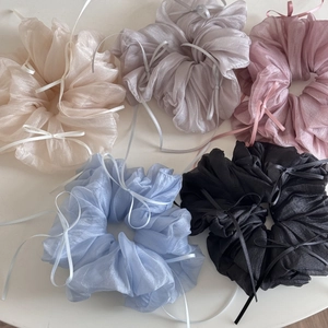 Detail of five oversized organza scrunchies in pastel colors with delicate ribbons
