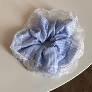 Detailed view of light blue striped fabric scrunchie with delicate white lace trim edge