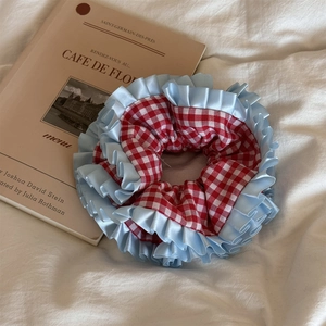 Détail d'un chouchou à carreaux rouges avec des bords à volants bleu clair sur tissu