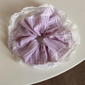 Close-up of a purple and white striped hair scrunchie with delicate white lace edges