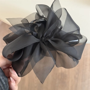 Detailansicht der schwarzen Haarklammer mit Schleife aus Netzstoff und mehrlagigem Chiffon-Design