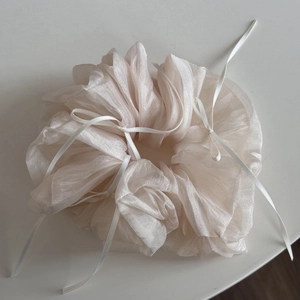 Detail of a large cream organza scrunchie with delicate white ribbon bow accents