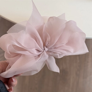 Detail der Lagen aus durchscheinendem rosa Organza-Stoff und das Schleifendesign der Haarklammer