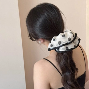 Close-up of a chiffon polka dot hair scrunchie with black ribbon bow on a ponytail