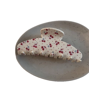 Grande pince à cheveux crème avec motif cerise et strass sur une assiette en céramique