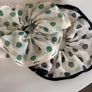 Detail view of large chiffon polka dot hair scrunchies with white and green patterns