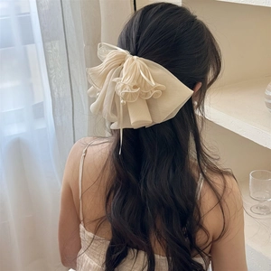 Détail d'une élégante pince à cheveux en mousseline crème avec nœud et perles délicates