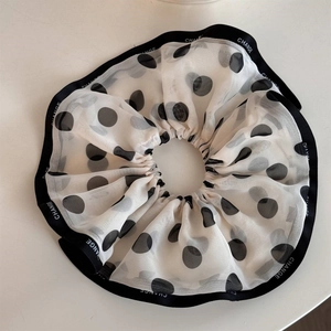 Detail of white chiffon scrunchie with black polka dots and Change logo webbing edge