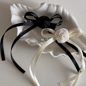 Detail of elegant black and white ribbon hair clips with fabric roses and rhinestones