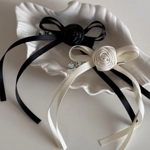Elegant rose ribbon bow hair clips set with crystals on a white decorative shell plate