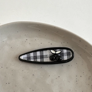 Detail der süßen Haarspange mit schwarz-weißem Karomuster und dekorativem Kirsch-Ornament