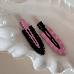 Nahaufnahme von Wellen-Haarspangen in Schwarz und Rosa Kontrastfarben in einer Schale