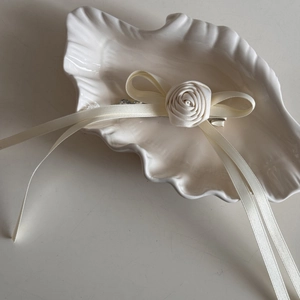 Detailed view of cream satin rose hair clip with long ribbons on a shell tray