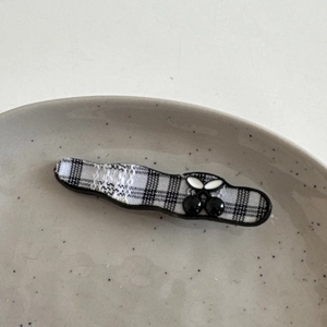 Detail der karierten welligen Haarklammer mit schwarzen Kirschanhängern auf Tablett