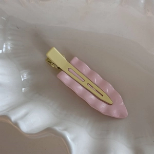 Nahaufnahme von wellenförmigen rosa und gelben Haarklammern auf einem Keramiktablett
